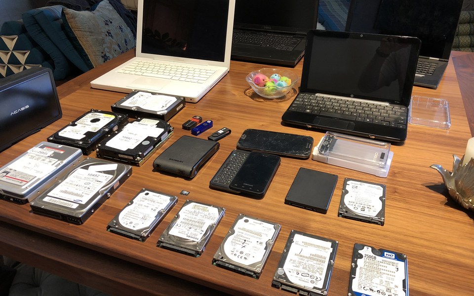 Laptops, phones, hardware wallets and hard drives arranged on a table