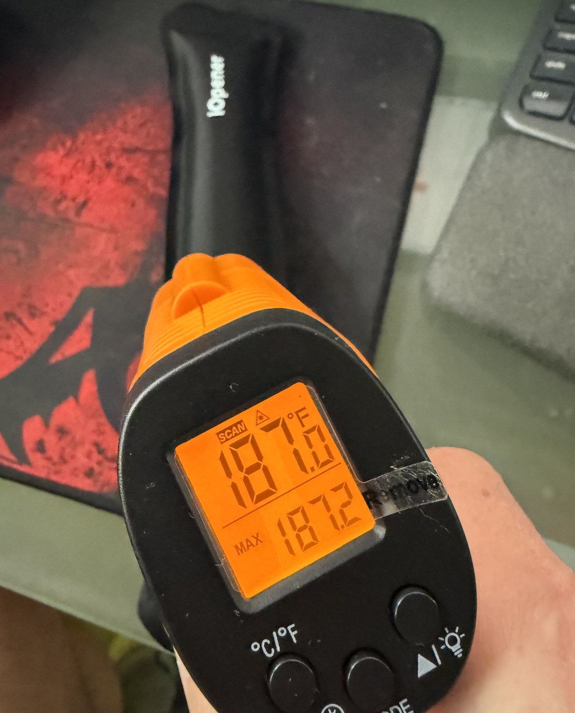 Infrared thermometer reading 187.0 F with a maximum of 187.2 F, pointed at the iFixit iOpener heat pack on the bench