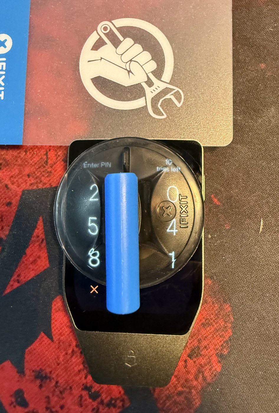 Suction handle attached to the Trezor Safe 7 touchscreen, which is showing the PIN keypad, with a thin plastic opening card resting above it