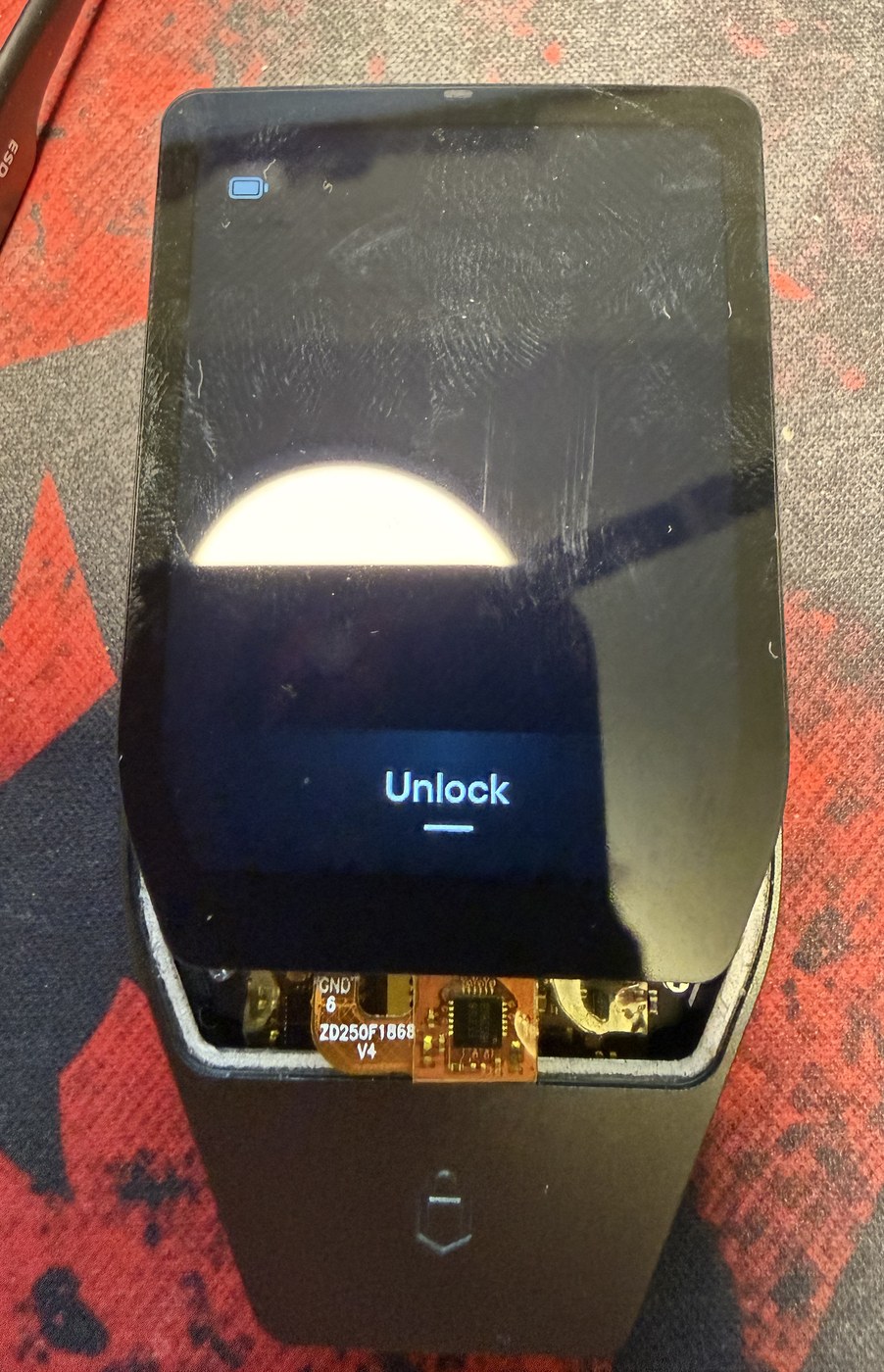 The transplanted Trezor Safe 7 mainboard seated in the donor enclosure with the display in place, booted to the Unlock screen